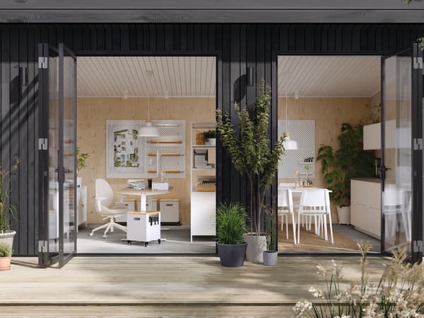 TROTTEN desks and other office furniture in a modern one-storey building with open French doors and a wooden deck outside.