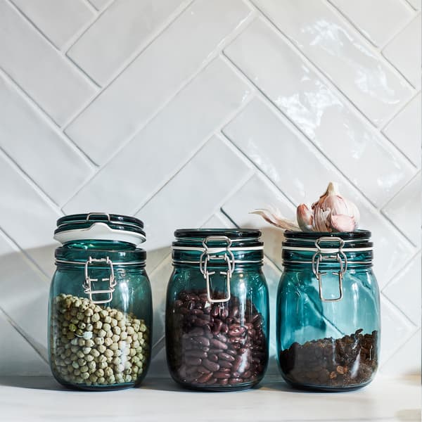 تساعد ثلاثة مرطبانات KORKEN من الزجاج الشفاف الأخضر في الحفاظ على الروائح العطرية والنكهات. زبيب مجفف وفاصوليا مخزّنان في الداخل.