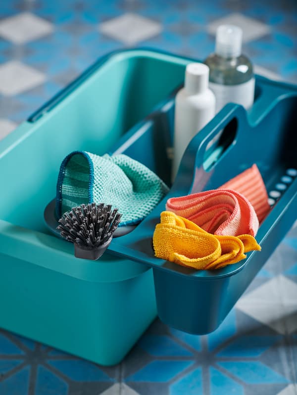 Türkiz PEPPRIG vödröt látunk, amely tárolójában PEPPRIG kendők, szivacsok és tiszt-ítószerek vannak.