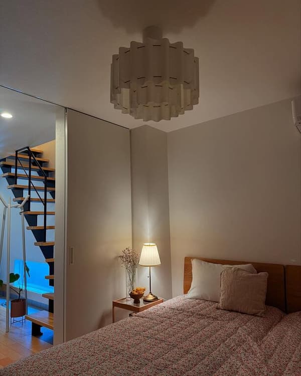 Tunnelmallinen makuuhuone, jossa on IKEA STOCKHOLM 2025 -kattovalaisin ja ÅRSTID-pöytävalaisin.