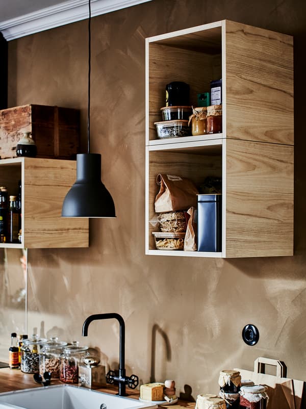 TUTEMO elementi ispunjeni različitim kuhinjskim dodacima raspoređeni su neravnomjerno po zidu iznad kuhinjice.