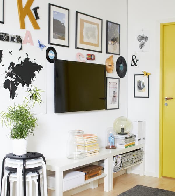 TV fixée au mur et entourée de reproductions sous cadre, pour créer un effet galerie.