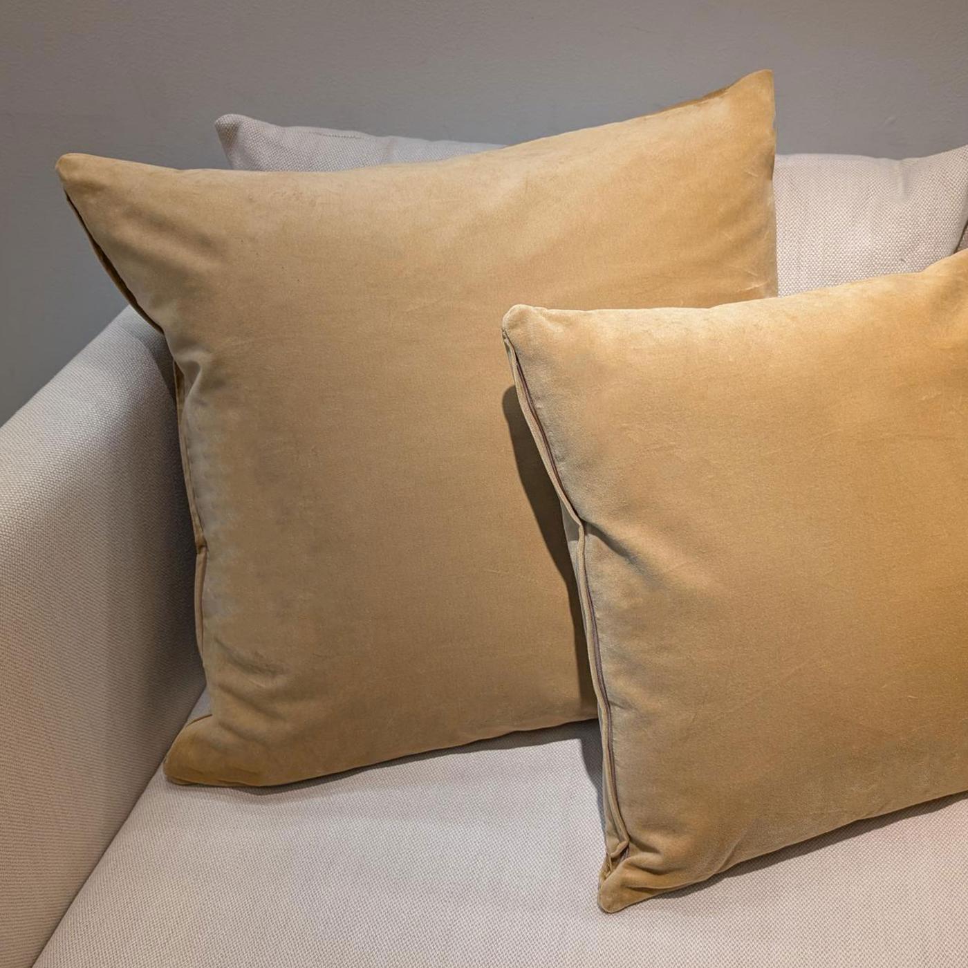 Två gulbruna SANELA sammetskuddar i två olika storlekar i en ljusbeige soffa.