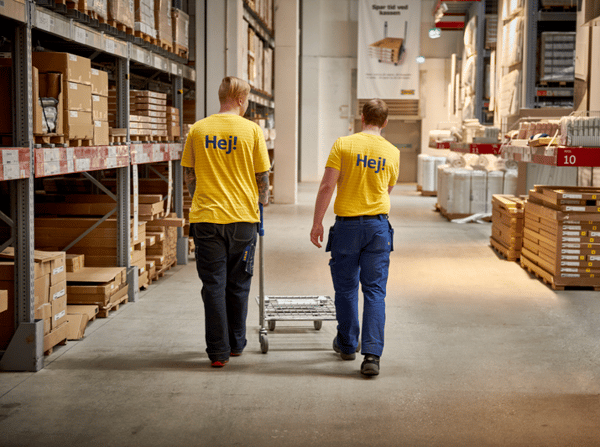 Två IKEA medarbetare som går i IKEA varuhuset och plockar varor.