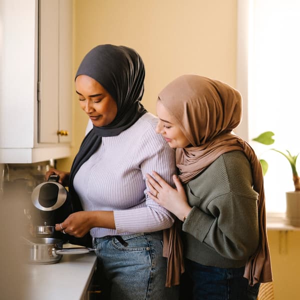 Två kvinnor med hijab som häller kaffe.