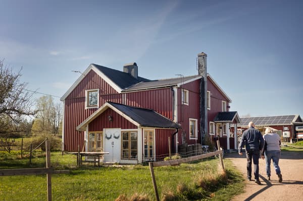 Två personer går mot ett rött trähus. 