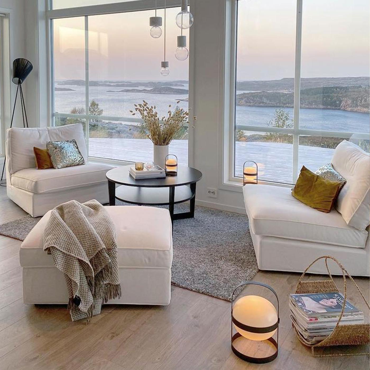 Två vita KIVIK fåtöljer tillsammans med en fotpall i stort modernt vardagsrum i vitt. 2025-11.