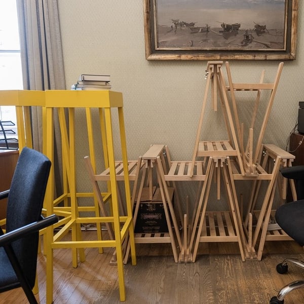 Творческое рабочее пространство с деревянными табуретами, сложенной мебелью и настенным искусством