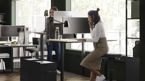 twee dames zijn aan het werk aan een stabureau halfzittend op een hoge kruk