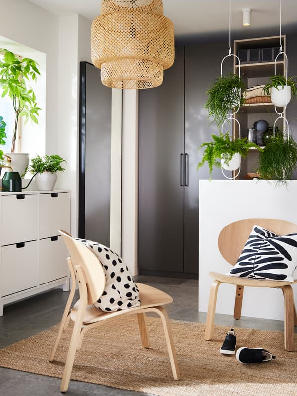 Twee FRÖSET stoelen met knusse MAJSMOTT kussens staan op een LOHALS vloerkleed. Tegen de verste muur staan donkergrijze PAX kledingkasten.