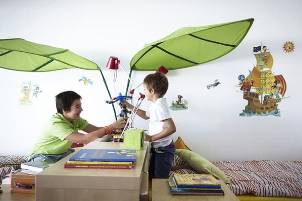 Twee kinderen spelen samen met speelgoed op de kast die hun slaapkamer verdeelt