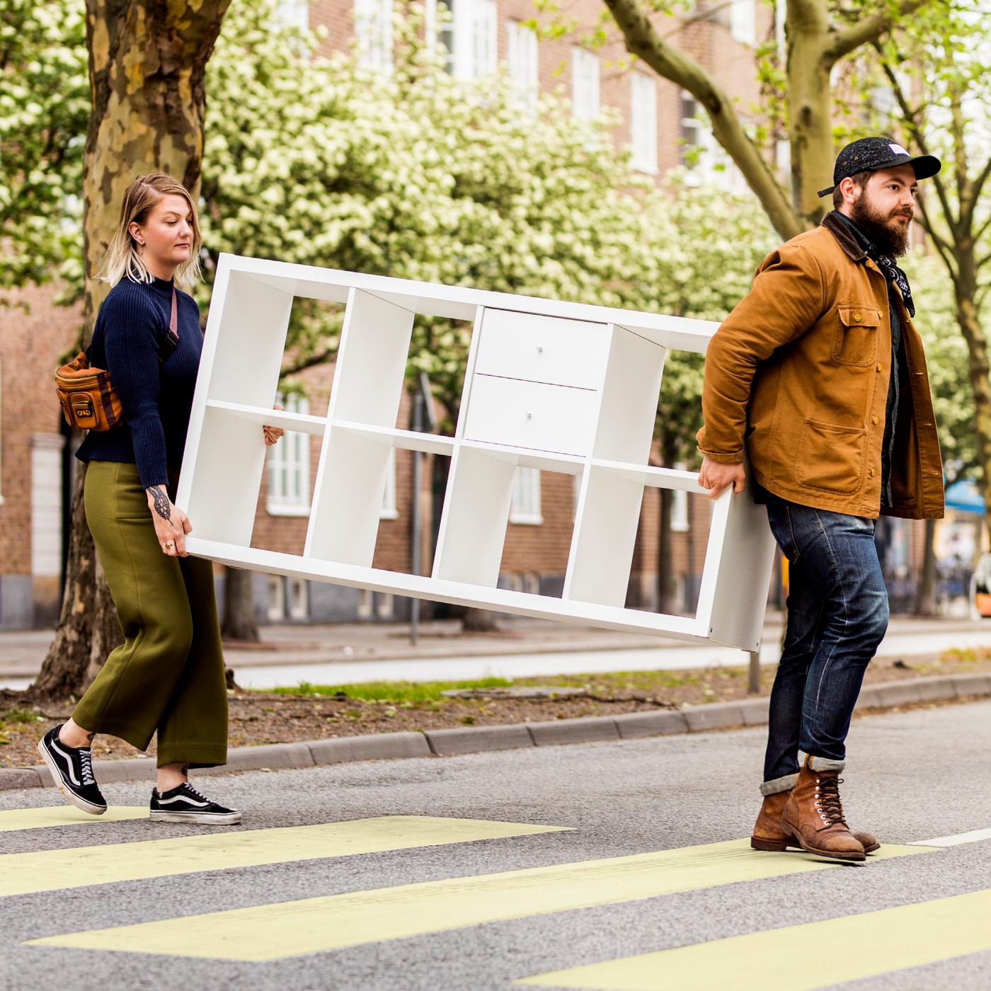 Twee mensen lopend met een KALLAX kast