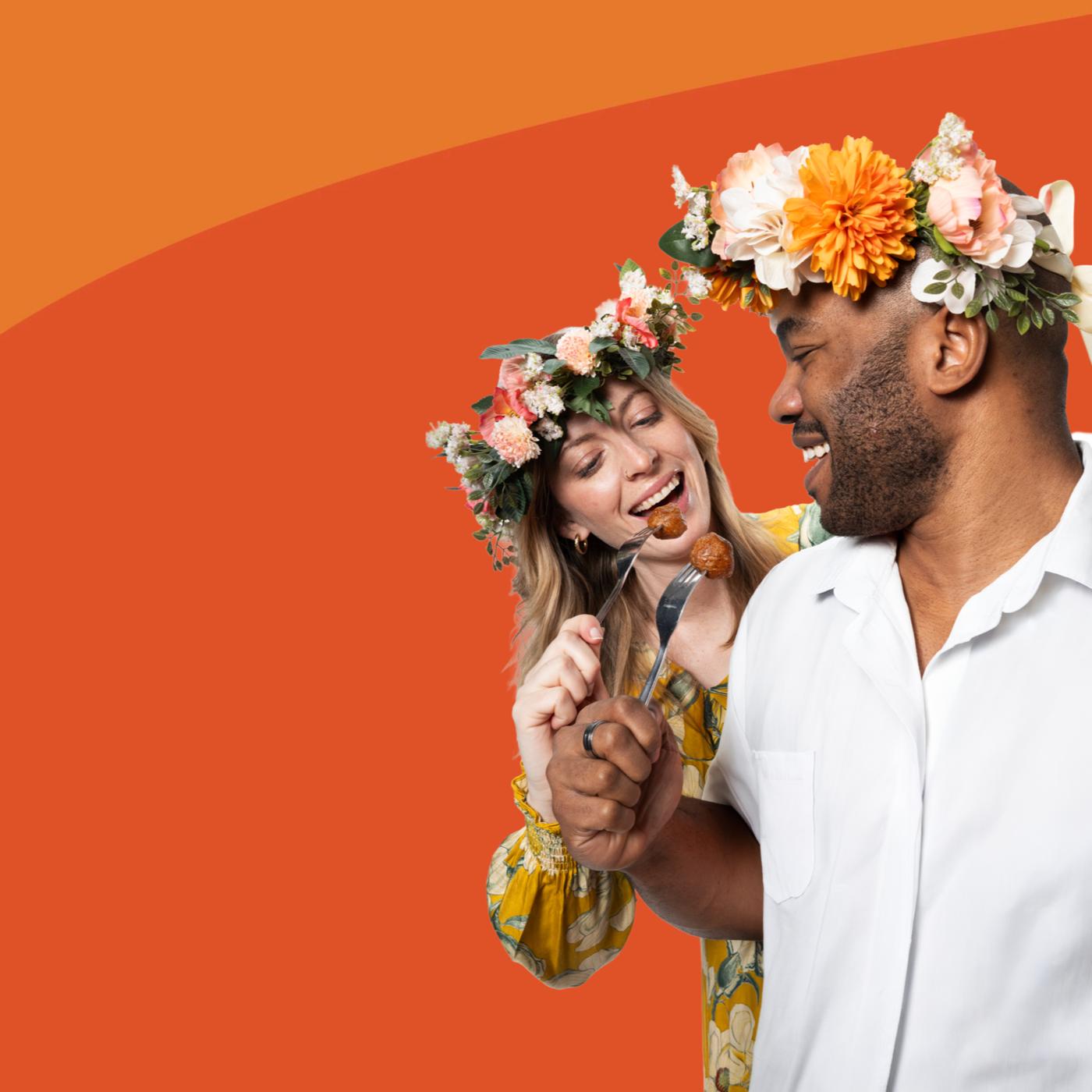 twee mensen met bloemenkransen en gehaktballen in hun mond