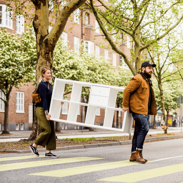 Twee mensen steken de straat over met een IKEA KALLAX-kast.
