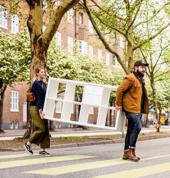 Twee mensen tillen een KALLAX kast