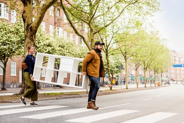 Twee mensen tillen een KALLAX kast over de straat
