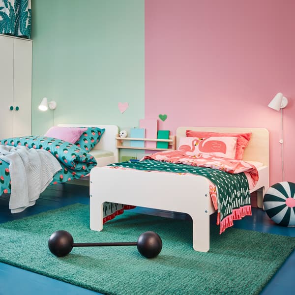 Twee SLÄKT bedframes met verschillende hoofdborden: een in wit en een in berken. Beide zijn voorzien van kleurrijk beddengoed.