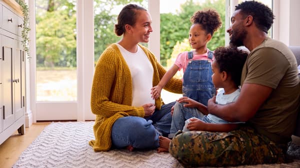 Two adults sitting on the floor with two children talking