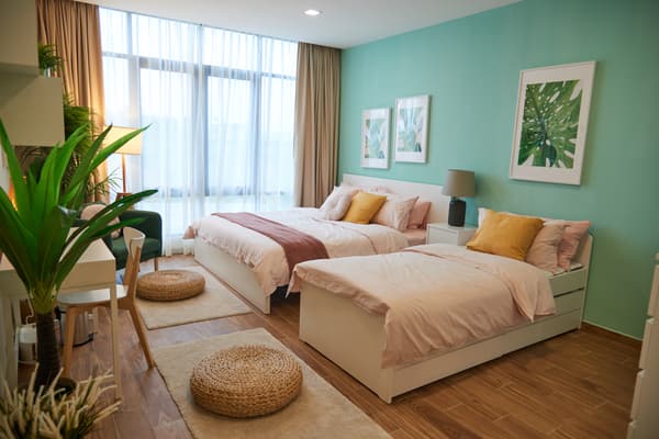 Two beds are placed against a turqoise wall.