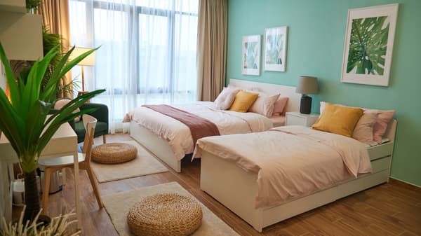 Two beds are placed against a turqoise wall.