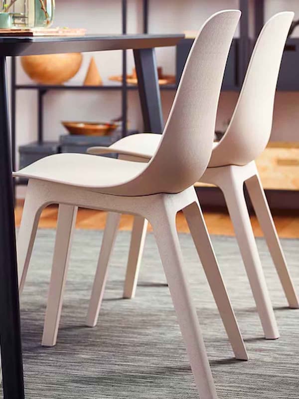 Two beige ODGER dining chairs tucked under a dining table in the dining area of the home.