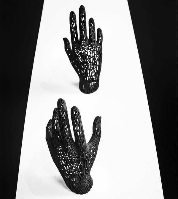 Two black 3D-printed hand-shaped decorations mounted on a wall.