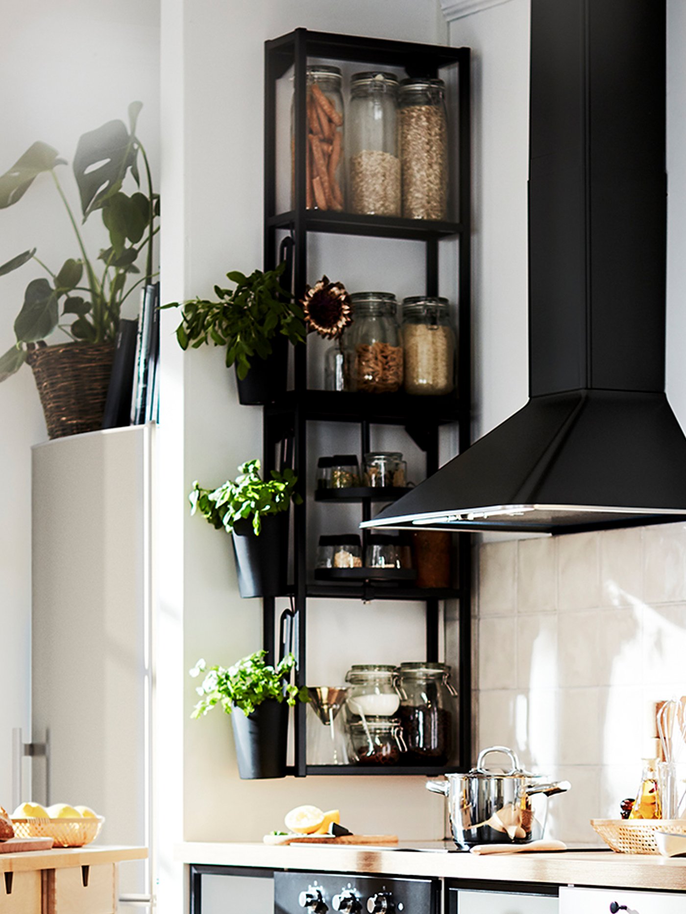 Two, black, ENHET wall frames with shelves, mounted on a kitchen corner wall, next to a black, wall mounted extractor hood.
