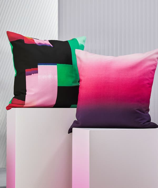 Two brightly-colored cushions on white pedestals.