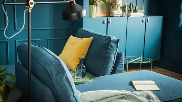Two chaise longues furnishing a living room that’s painted in deep shades of blue.