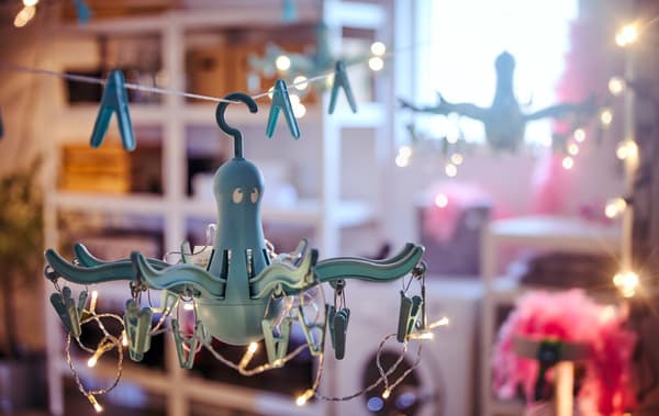 Two chandeliers made from hang dryers and lighting chains, hung in a garage interior with washer and various storage.