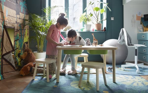 Two children drawing on a children’s IKEA table  in a playroom.