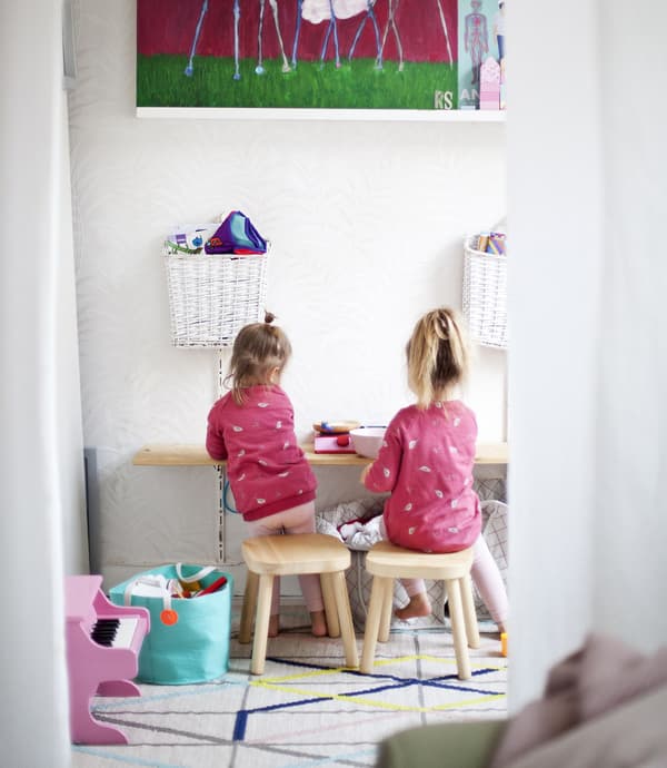 Two children sitting on stools in a play area.