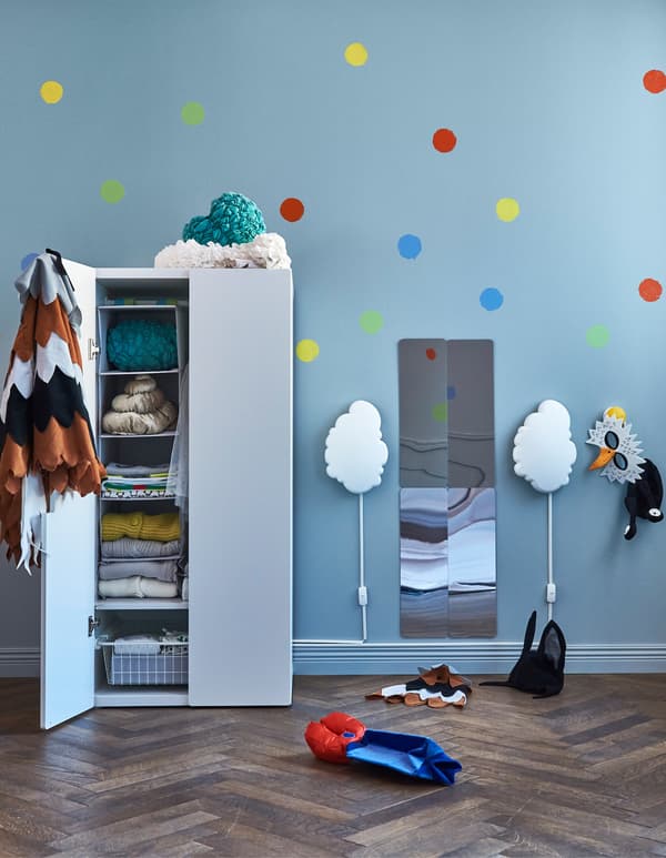 Two cloud-shaped wall lamps on each side of a mirror and next to a wardrobe in a child’s room