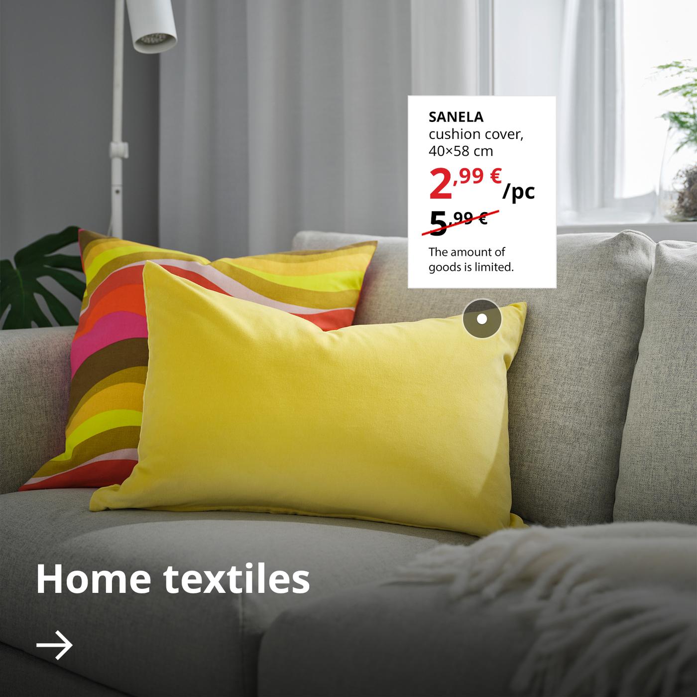 Two cushions in yellow and multicolour covers lie on a grey sofa. Next to them, on a white background, the sale price of the yellow SANELA cover is shown — 2,99 € (regular price 5,99 €). Below, there is an arrow with the text “Home textiles”.