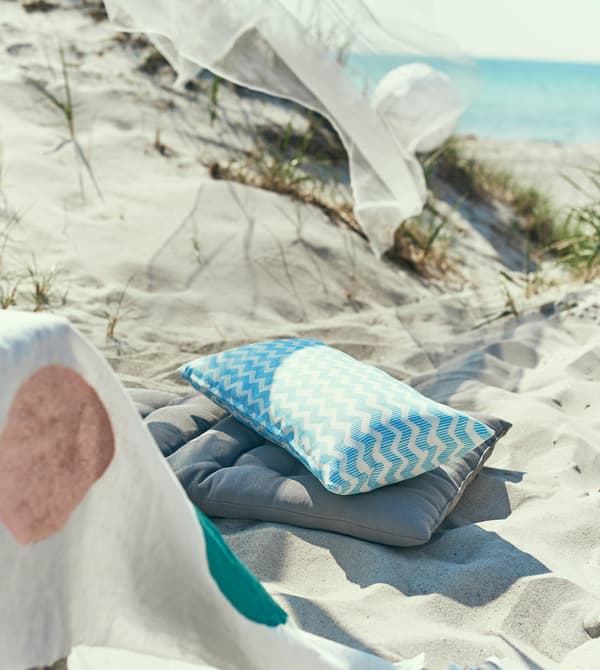 Two cushions sit in the sand.