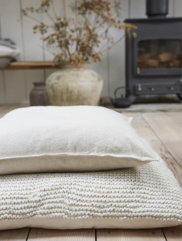 Two cushions stacked on wooden floorboards.