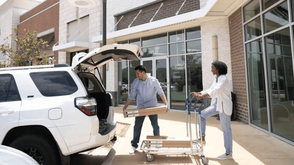 Two customers are loading their IKEA product into the back of an SUV