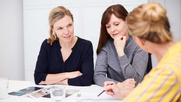 Two customers discussing their plans with an IKEA salesperson at a table.