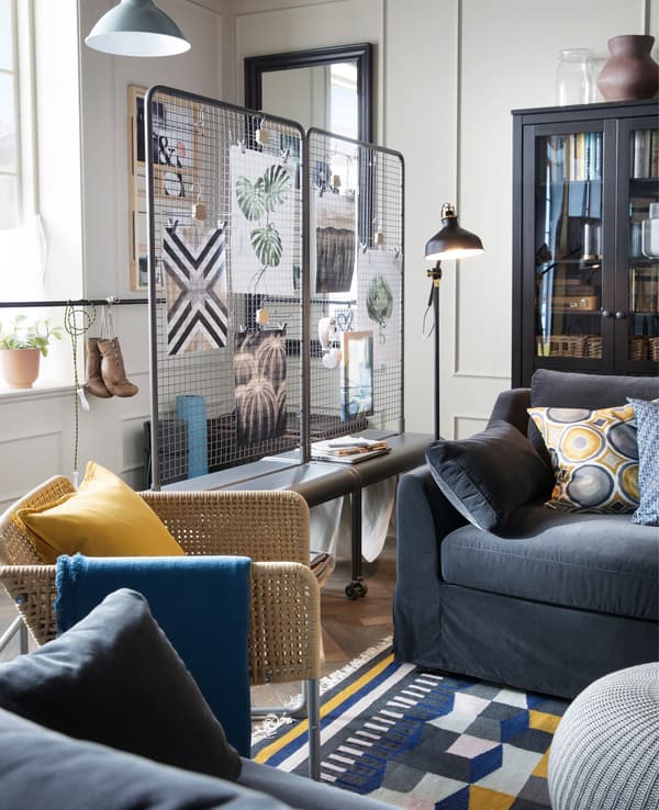 Two dark grey sofas facing each other, a wicker armchair and lots of colourful cushions in a living room.