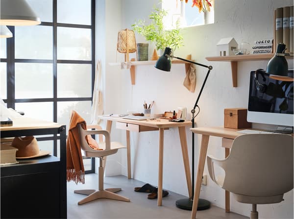 Two desks in ash veneer with white/beige swivel chairs, a black floor lamp between them and two wall shelves in ash veneer.