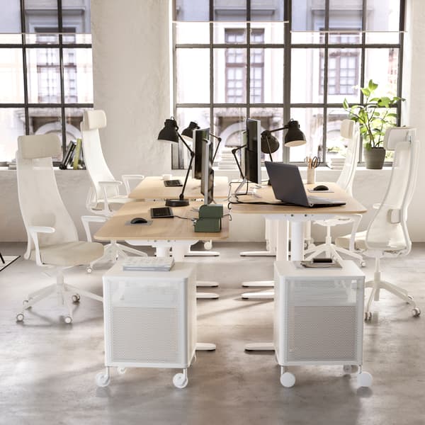 Two desks standing opposite each other, white storage cabinets on wheels, beige/white ergonomic chairs, black desk lamps.