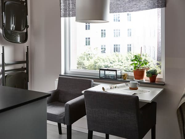 Two drop-leaf tables on a kitchen wall, with one up for single-person seating.