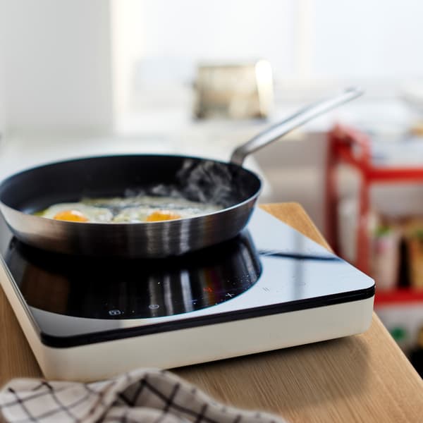 Two fried eggs in an IKEA 365 frying pan standing on energy-efficient TILLREDA portable cooktop