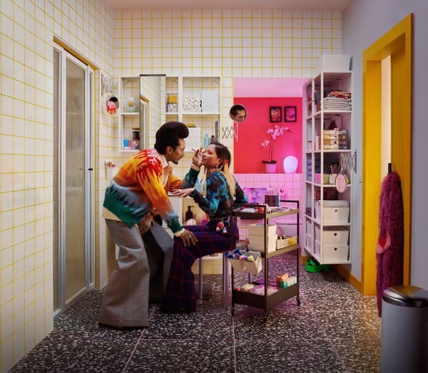 Two friends applying make-up in a bedroom with white, pink and yellow colours.