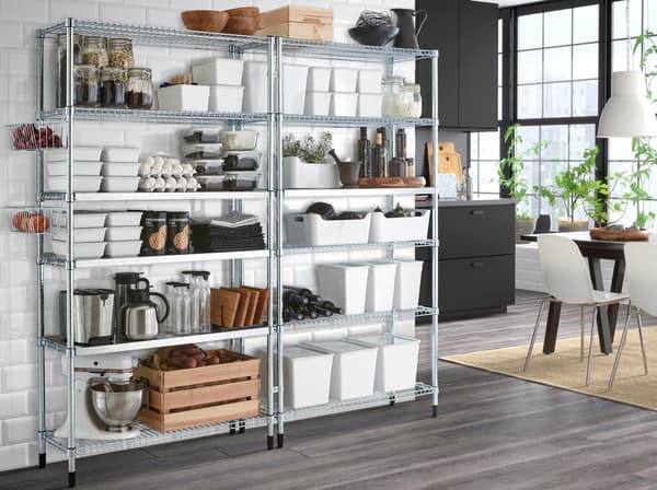 Two galvanised OMAR shelving units against a white wall with a spacious dark grey kitchen in the background.