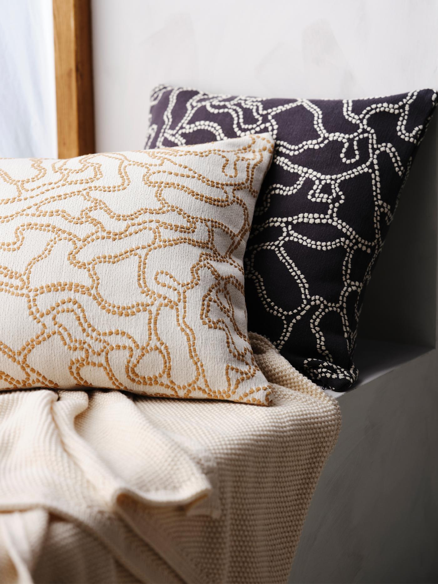 Two GULDFLY cushions, one in anthracite with an off-white pattern and one in off-white with a yellow-beige pattern.