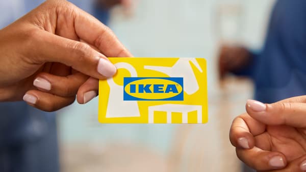 Two hands are passing around a yellow IKEA card.