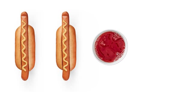 Two hot dogs with mustard and a full glass of red drink.