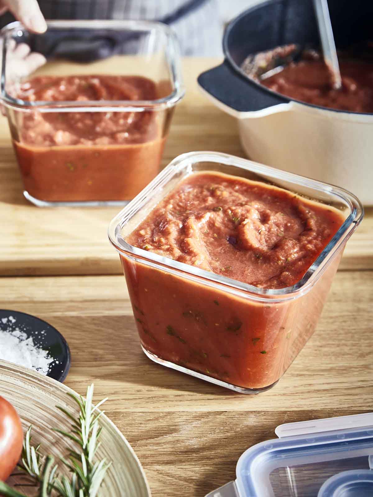 Two IKEA 365+ glass containers filled with tomato sauce on a kitchen island.