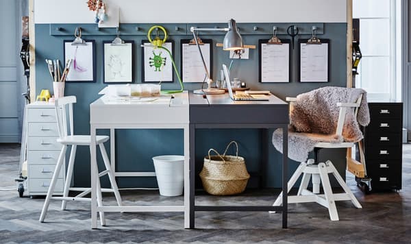 Two IKEA ALEX desks face are placed to face each other. One of the workspaces is arranged for a parent, and the other is for a young child.